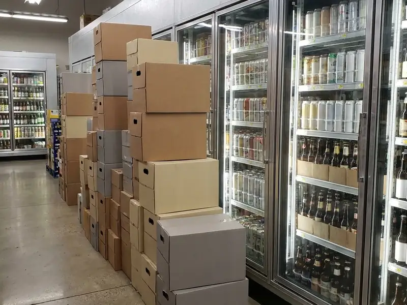 Stacks of beer cases in front of glass-door beer coolers